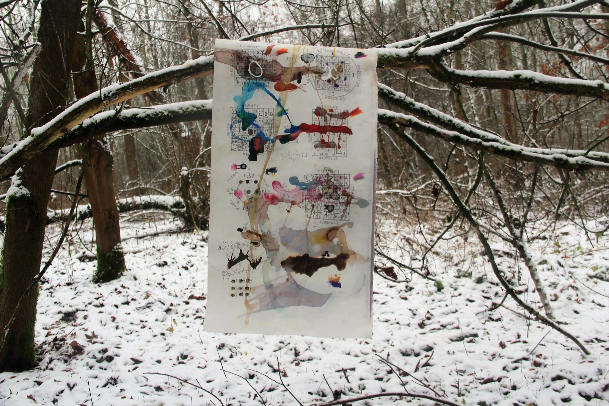 A work on a pale support suspended among branches in a snow-covered woodland
